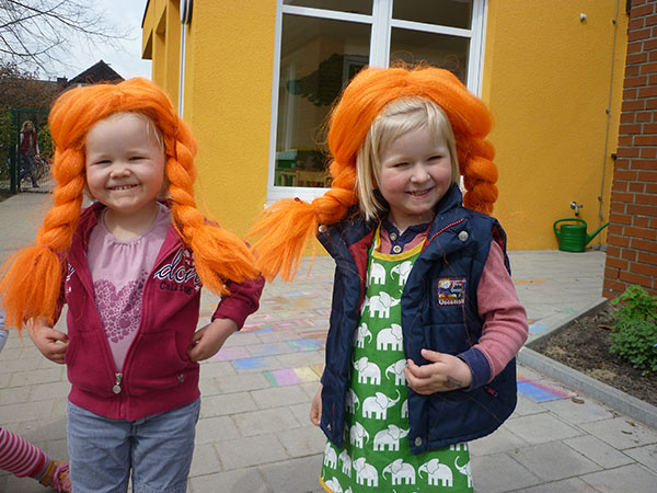 zwei Kinder haben eine Pippi Langstrumpf Perücke auf und freuen sich